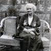 Thumbnail: Annie Shrimpton outside in garden on a chair posing for photograph.