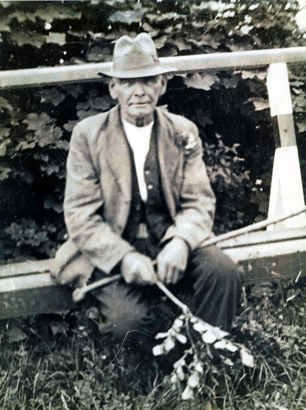 Thomas Jack Harris, grandfather of Kay Coles, sitting on the raised boardwalk running alongside the roadway.